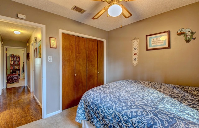 carpeted bedroom with a closet, visible vents, ceiling fan, a textured ceiling, and baseboards