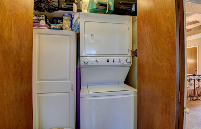 washroom with stacked washer and clothes dryer and cabinet space