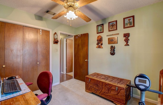 home office featuring light colored carpet, visible vents, ceiling fan, and a textured ceiling