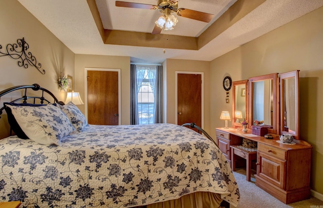 bedroom featuring a ceiling fan, a raised ceiling, and light carpet