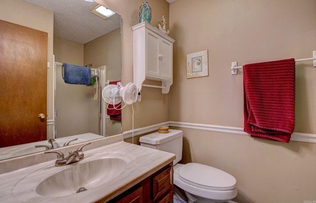 bathroom featuring toilet, a textured ceiling, and vanity