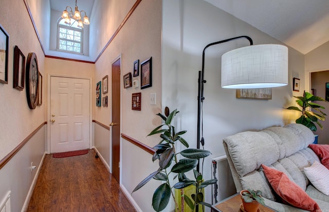 hallway featuring dark wood-type flooring, lofted ceiling, a chandelier, and baseboards