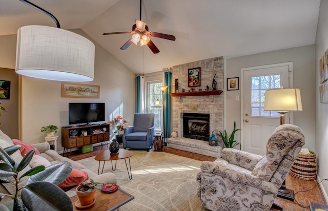 living area with a healthy amount of sunlight, a fireplace, wood finished floors, and lofted ceiling