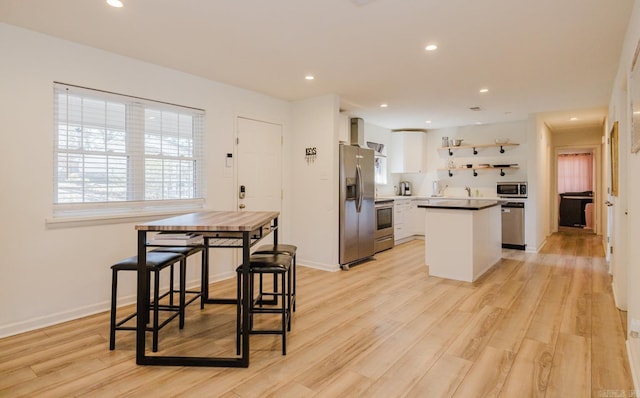 kitchen featuring a kitchen island, light wood-style floors, white cabinets, appliances with stainless steel finishes, and open shelves