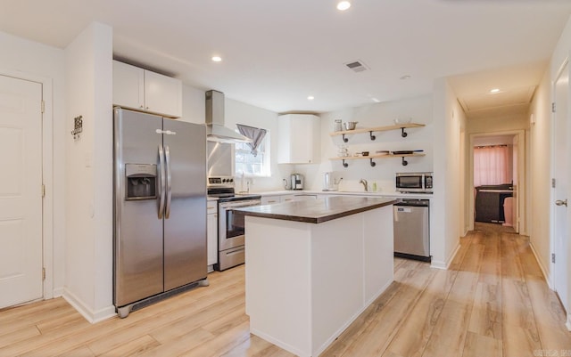 kitchen featuring stainless steel appliances, a kitchen island, white cabinets, wall chimney range hood, and open shelves