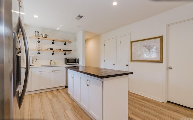 kitchen with open shelves, visible vents, appliances with stainless steel finishes, white cabinetry, and a kitchen island