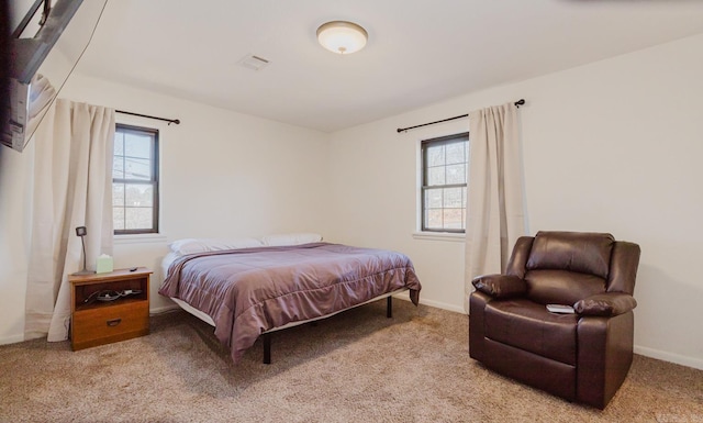 bedroom with baseboards, visible vents, and light colored carpet