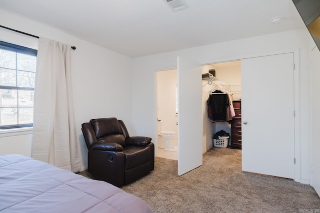 bedroom with a spacious closet, multiple windows, visible vents, and light colored carpet