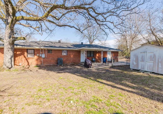 back of house with an outbuilding, brick siding, fence, a lawn, and a storage unit