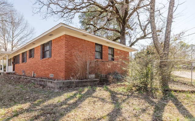 view of home's exterior featuring crawl space, fence, and brick siding