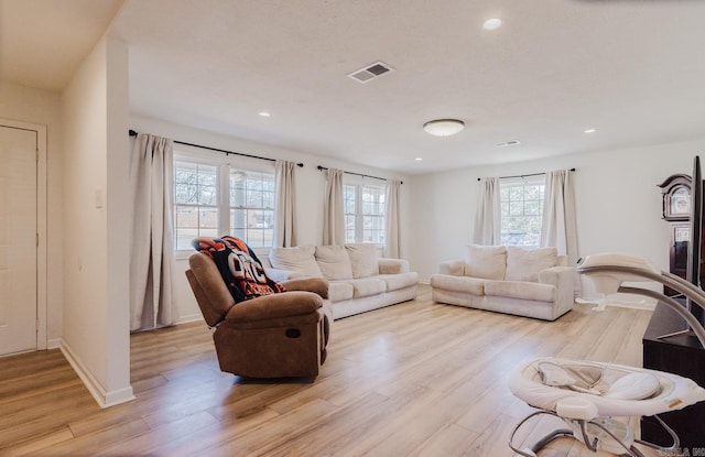 living room with light wood-type flooring, baseboards, and recessed lighting