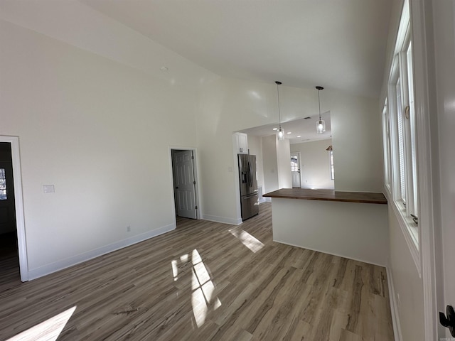 unfurnished living room with high vaulted ceiling, baseboards, and wood finished floors