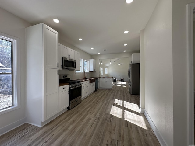 kitchen featuring stainless steel appliances, light wood-type flooring, white cabinets, and a sink