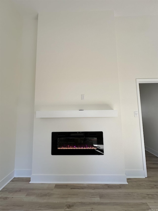 interior details with a glass covered fireplace, baseboards, and wood finished floors