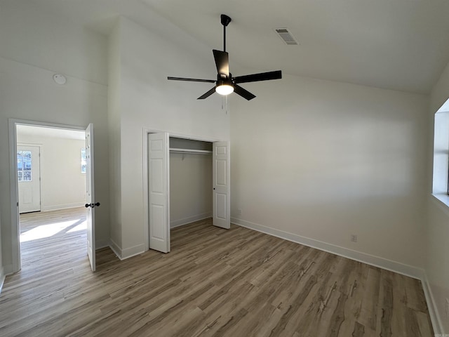 unfurnished bedroom featuring high vaulted ceiling, visible vents, baseboards, and wood finished floors