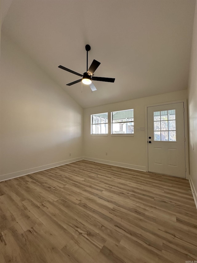 spare room with vaulted ceiling, a ceiling fan, light wood-style flooring, and baseboards