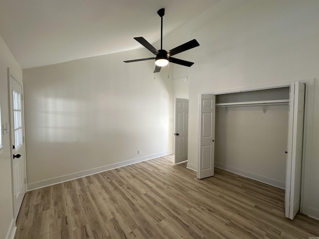 unfurnished bedroom featuring ceiling fan, high vaulted ceiling, light wood-style flooring, baseboards, and a closet