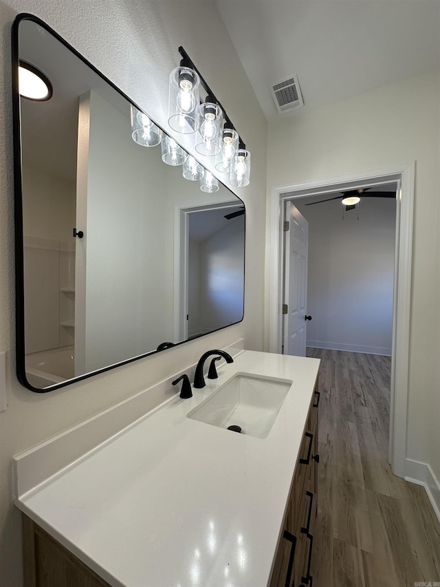 full bathroom with visible vents, washtub / shower combination, vanity, wood finished floors, and baseboards