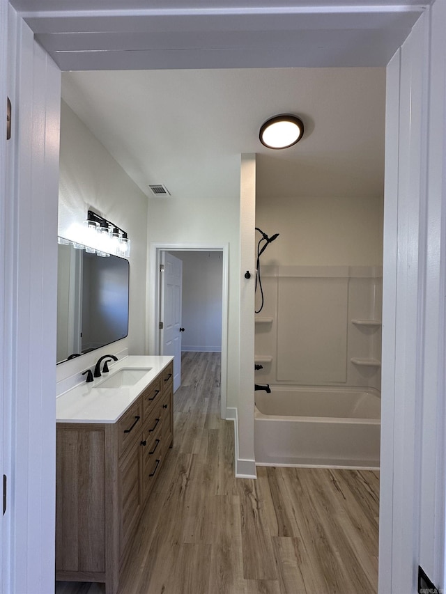 bathroom featuring washtub / shower combination, visible vents, wood finished floors, and vanity