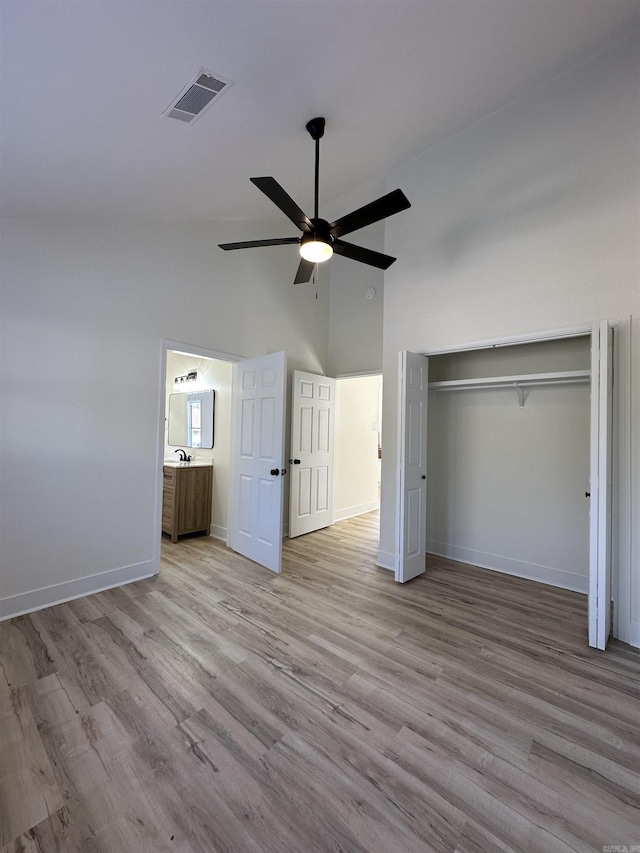 unfurnished bedroom featuring visible vents, baseboards, a ceiling fan, light wood-style flooring, and vaulted ceiling