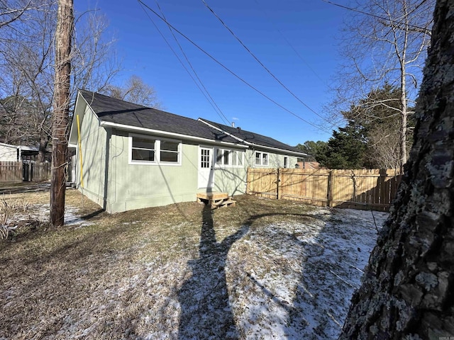 view of home's exterior with a shingled roof and fence