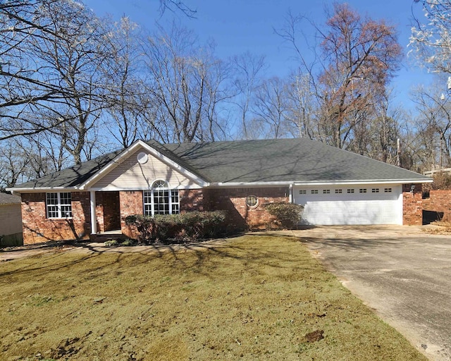 single story home featuring a front yard, concrete driveway, brick siding, and an attached garage