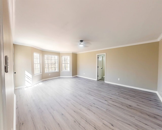 unfurnished room with ornamental molding, light wood-style flooring, and baseboards