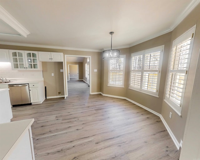 unfurnished dining area with baseboards, light wood-style flooring, and crown molding