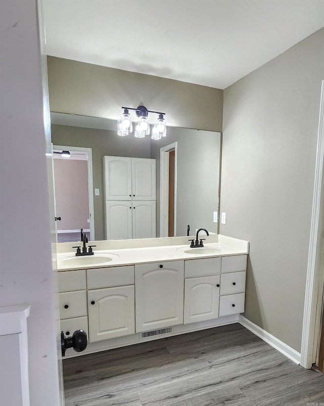 bathroom featuring double vanity, wood finished floors, a sink, and visible vents