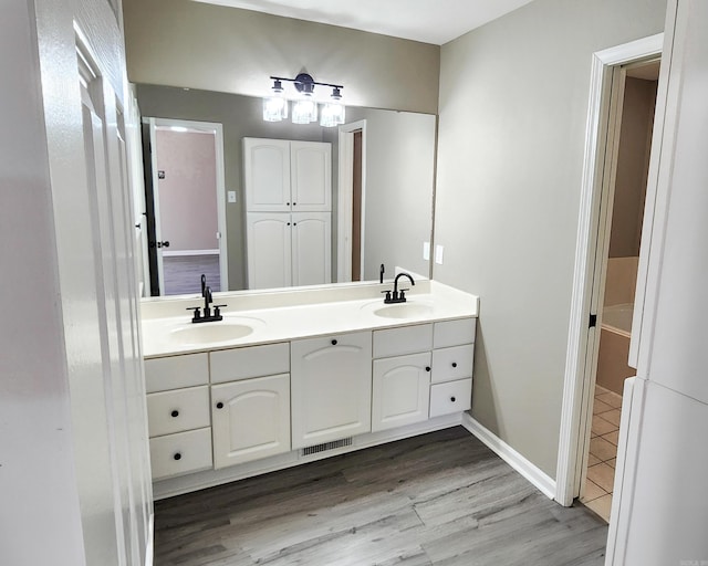 full bath featuring double vanity, a sink, and wood finished floors