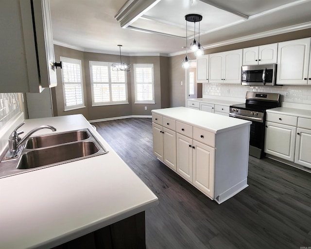 kitchen with a kitchen island, appliances with stainless steel finishes, light countertops, white cabinetry, and a sink