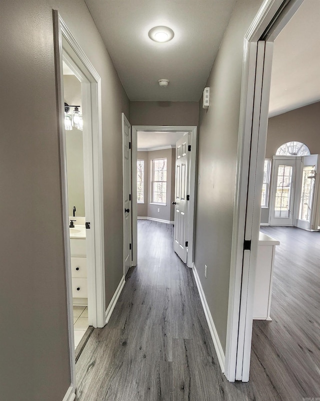 corridor with a sink, baseboards, and wood finished floors