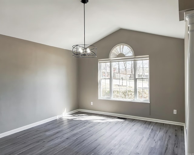 unfurnished room featuring lofted ceiling, a notable chandelier, wood finished floors, visible vents, and baseboards