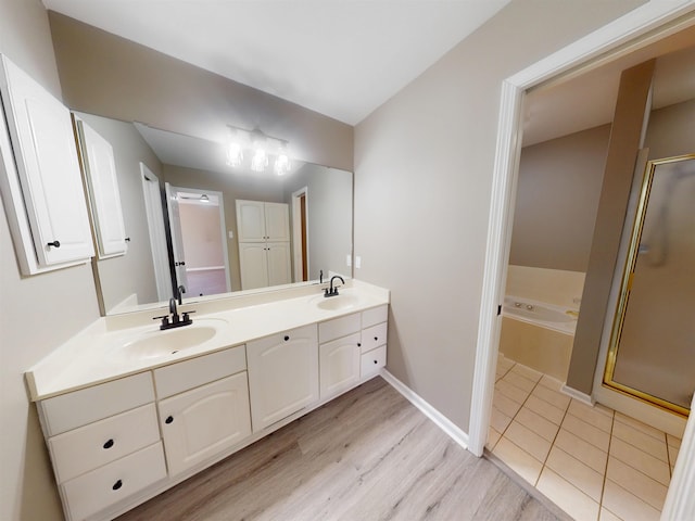 bathroom featuring double vanity, wood finished floors, a sink, and a bath