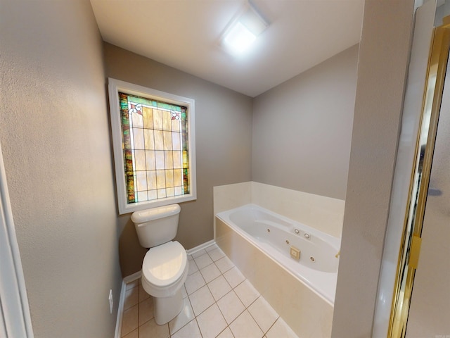 bathroom featuring baseboards, a tub with jets, toilet, and tile patterned floors