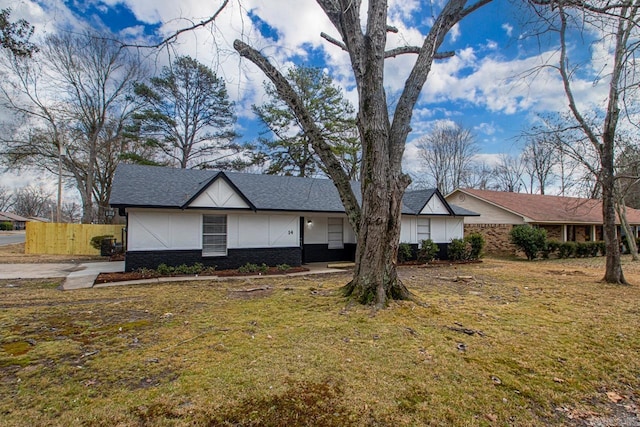 view of front facade featuring brick siding, a shingled roof, fence, and a front yard