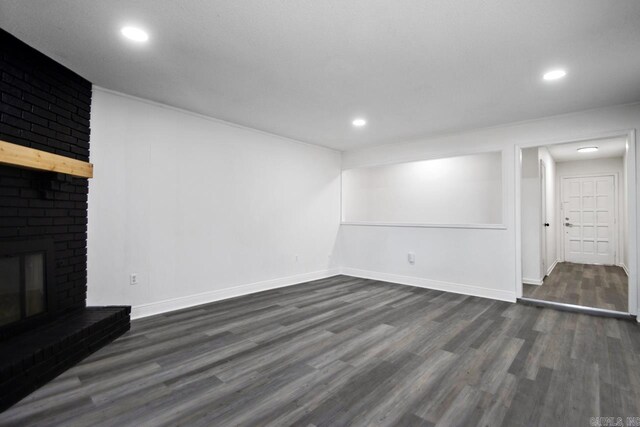 below grade area featuring dark wood-type flooring, recessed lighting, a brick fireplace, and baseboards