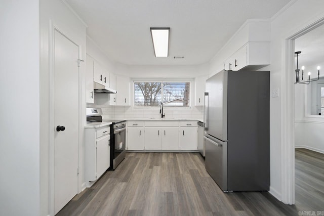 kitchen with stainless steel appliances, light countertops, decorative backsplash, white cabinetry, and under cabinet range hood