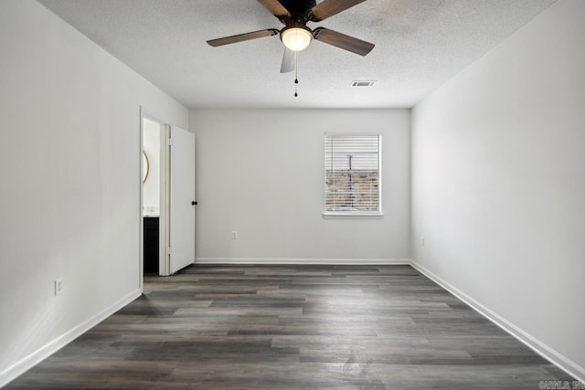 spare room featuring dark wood-style floors, a textured ceiling, visible vents, and baseboards