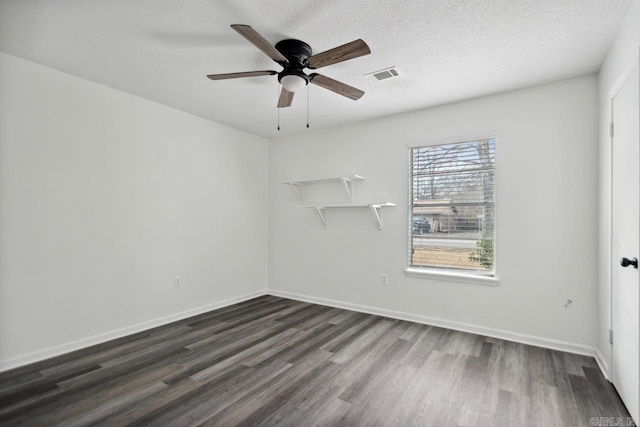 unfurnished room with a textured ceiling, dark wood-type flooring, visible vents, and baseboards