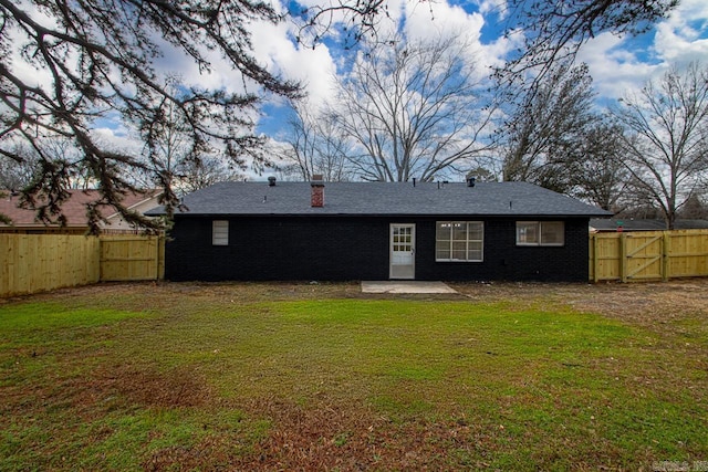 rear view of property featuring brick siding, a fenced backyard, and a yard