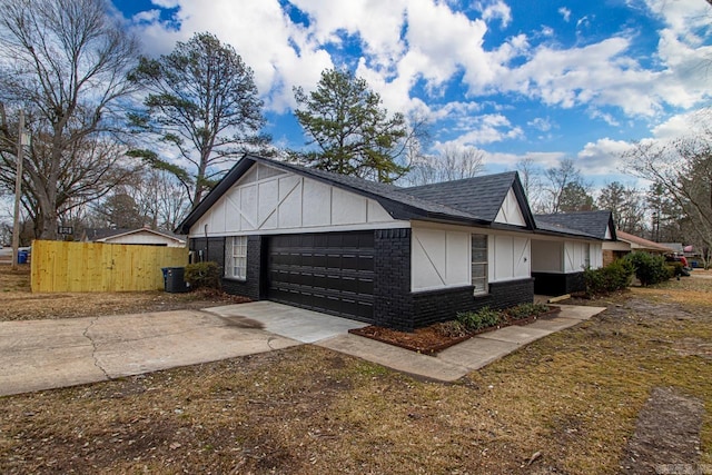 view of side of property with brick siding, a shingled roof, an attached garage, fence, and driveway