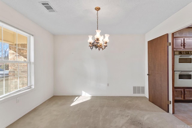 unfurnished dining area featuring an inviting chandelier, visible vents, and a healthy amount of sunlight