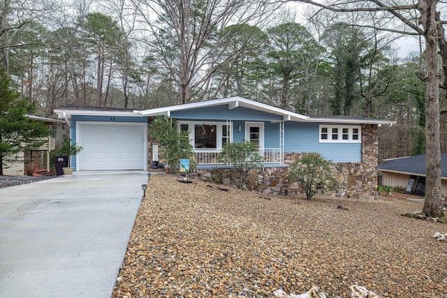 ranch-style house featuring stone siding, a porch, an attached garage, and driveway