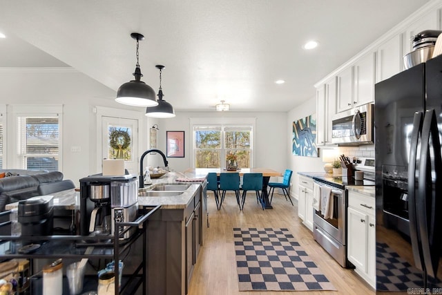 kitchen featuring appliances with stainless steel finishes, a kitchen island with sink, white cabinetry, and light stone counters