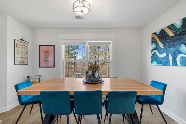 dining room with light wood-type flooring, baseboards, and visible vents