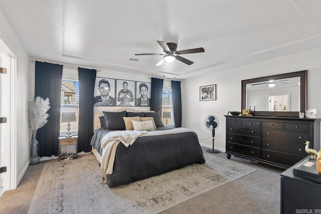 carpeted bedroom featuring a ceiling fan, multiple windows, visible vents, and baseboards