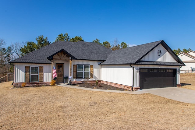 modern farmhouse style home featuring concrete driveway, a front lawn, roof with shingles, and an attached garage