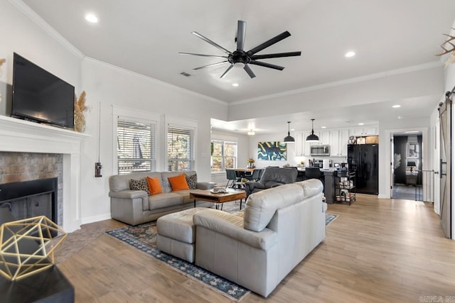 living area featuring light wood-type flooring, a fireplace, visible vents, and crown molding