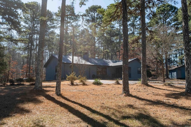 view of property exterior featuring a garage, metal roof, a lawn, and a chimney